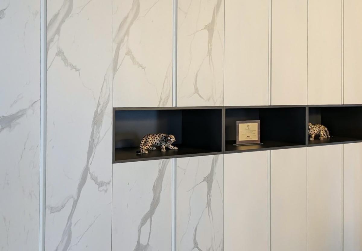 Sala Meeting Magrini Energia · Boiserie effetto marmo con nicchie nere e giaguaro in ceramica
